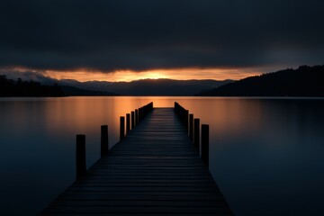 Fototapeta premium Pier extending into calm lake at sunset over distant hills