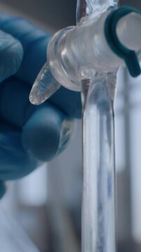 Vertical shot of chemist opening stopcock on separating funnel, adding liquid. Professional scientist conducts chemical experiment using lab device. Chemistry concept.