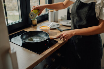 Chef pouring oil into frying pan in kitchen