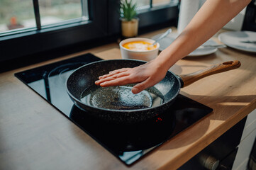 Chef checking frying pan temperature on induction stove top