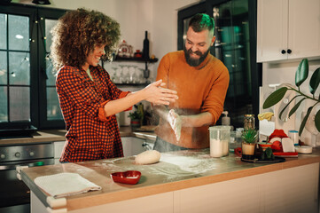 Couple having fun while preparing dough in kitchen at home