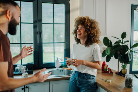 Couple talking and laughing in kitchen while having coffee