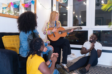 Friends playing acoustic guitar and clapping at home party