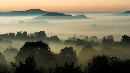 Obraz premium A foggy morning with silhouettes of distant hills barely visible through the mist