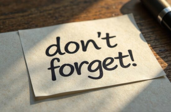 A handwritten reminder note saying don't forget rests on a wooden table next to a pen. The warm light casts a soft glow on the note, emphasizing the friendly message.