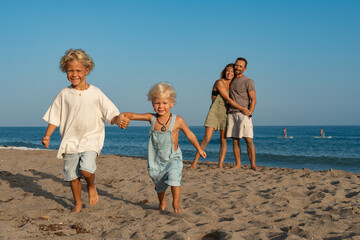 Children Running on the Beach with Parents Watching