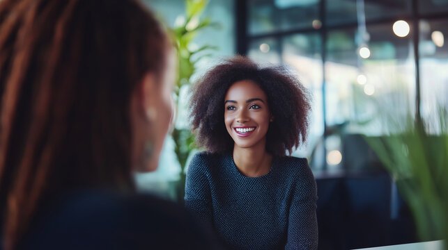 Hr professional smiles while discussing recruitment practices with a new hire in a modern office environment