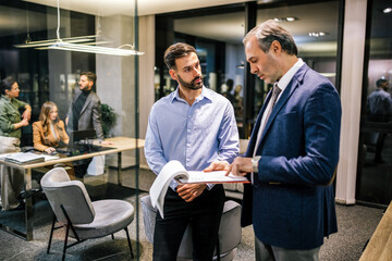 Two businessman finishing paperwork in their office during a meeting.