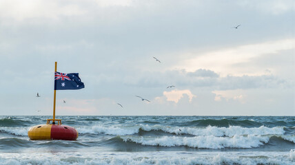 Australian flag on a buoy floating in the ocean with seagulls