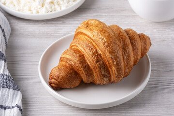 Delightful breakfast with croissant, cottage cheese, and coffee on a wooden table
