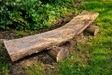 A bench made with tree trunks in a forest.
Outdoor bench made of wood logs.
