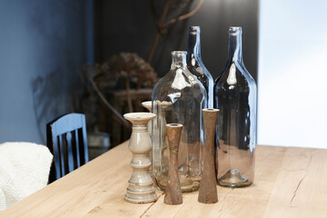 Wooden table with decorative glass bottles and ceramic candle holders.  Rustic, homey decor.