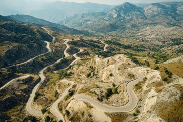 Aerial view of a winding mountain road with steep cliffs and lush vegetation