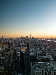 Aerial view of Fifth Avenue, Flatiron District, New York City with Manhattan skyline illuminated by with vibrant orange sunset and crescent moon in dusky blue sky