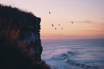 Coastal view at sunset with waves crashing and birds flying over cliffs in a serene seaside...