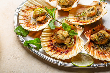Baked scallops with breadcrumbs, lime, parsley and mint. Close-up, light background.