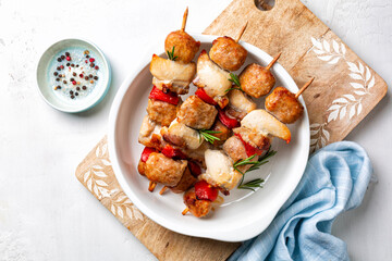 Meat skewers directly above on a white taable. Chicken, italian sausage, bacon and vegetable, bell peppers kebabs. Mediterranean kabob, summer food with rosemary.