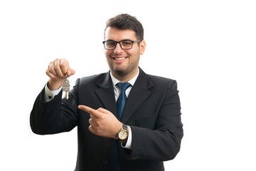 Real estate agent with friendly expression pointing house keys