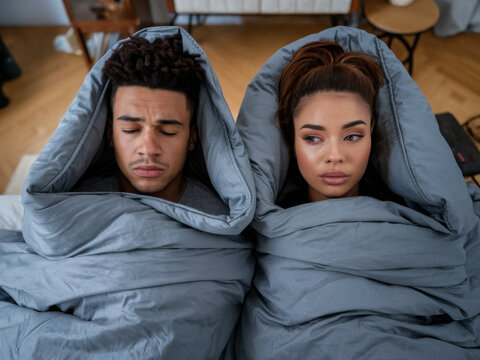 Joven pareja negra con expresiones fr&iacute;as. Est&aacute;n cubiertos por una manta
