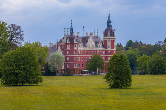 Bad Muskau, Germany - May 3 2024: Beautiful and majestic Hermann von P&uuml;ckler's Castle at center of Muskau park with beautiful green glades around and reflecting in small pond
