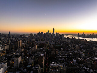 One World Trade Center, Lower Manhattan and NoMad district gleam at sunset with a crescent moon and Upper New York Bay in the background