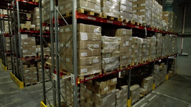 High shelf with finished products in large company warehouse. Stacks of boxes allow compact storage of material on different locations