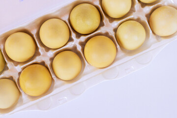 Dozen yellow eggs nestled neatly in egg carton ready to be used for cooking, baking