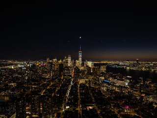 Stunning aerial perspective of the illuminated New York City skyline at night, with one world trade center and the sparkling cityscape of Lower East Side, Manhattan