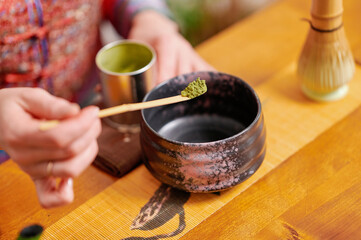 Green cast iron teapot, bamboo whisk, and ceramic bowl on bamboo mat, evoking tradition and serenity in a Japanese tea ceremony setting with rustic charm