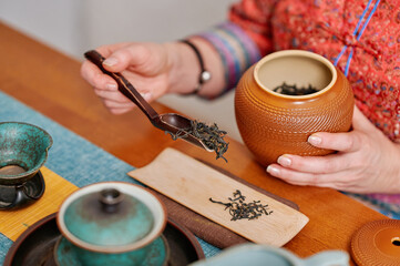 Fototapeta na wymiar Mindful tea-making in a quiet and intentional atmosphere. A woman blends traditional methods with modern calm, using handcrafted ceramic teaware to create a soothing cultural experience