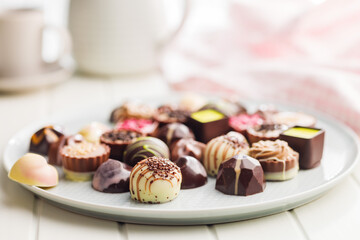 Mix of chocolate pralines on plate on white table.