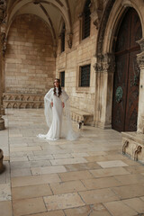 Naklejka premium beautiful bride dressed in a white dress stands in the middle of the old town. wedding photoshoot in the old town of Croatia. old medieval castle