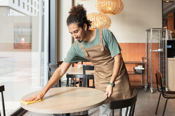Cafe worker diligently cleaning a table in a cozy environment