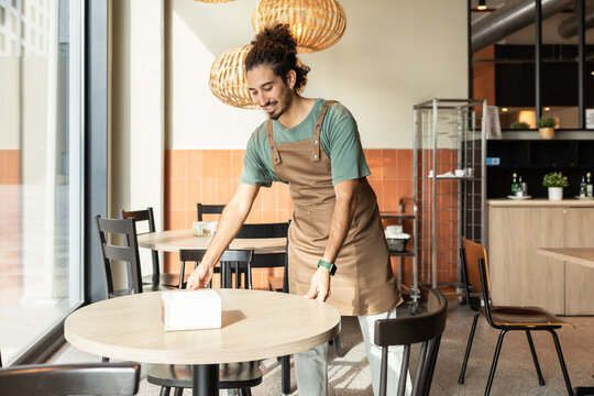 Cafe Employee Setting Up Tables in a Cozy Coffee Shop