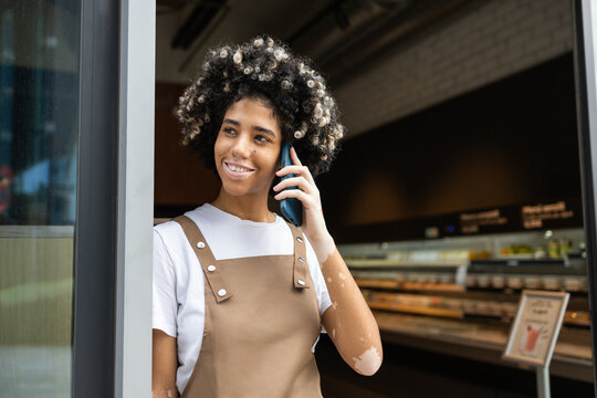 Cafe worker with phone smiling, casual workday scene