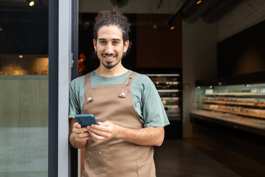 Smiling worker using smartphone in cozy cafe interior