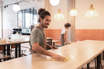 Cafe workers tidying tables in a modern coffee shop setting