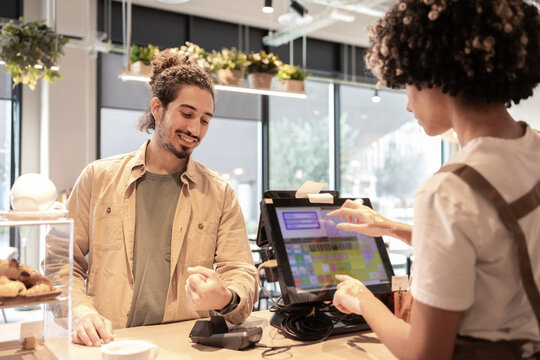 Friendly interaction between cafe cashier and customer at POS terminal