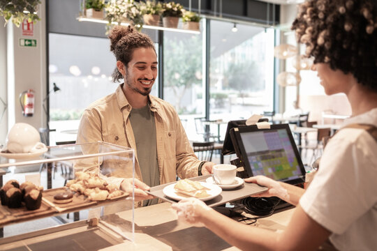Cafe worker serving coffee and pastry with a smile - Powered by Adobe
