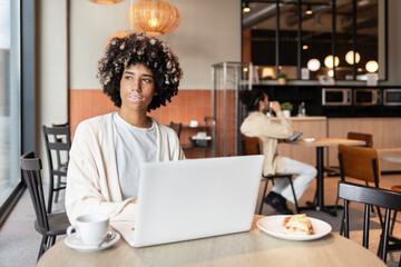 Young professional working on laptop in modern cafe setting