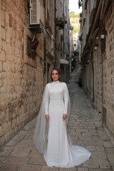 beautiful bride dressed in a white dress stands in the middle of the old town. wedding photoshoot in the old town of Croatia. old medieval castle