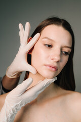 Fototapeta premium Correcting face treatment for aesthetic and beautiful shape. Female contour plastic. Correcting the shape of the skin face of young woman by beautician.