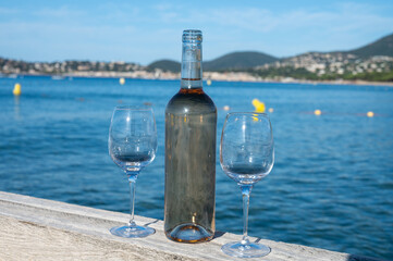 Tasting of cold rose wine from Provence outdoor on wooden yacht pier with view on blue water and white sandy beach Plage de Pampelonne near Saint-Tropez, summer vacation in France