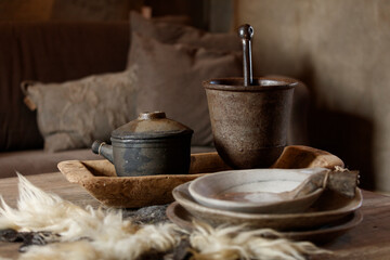 Rustic, handcrafted pottery and wooden bowls sit on a table, alongside wool fibers.  Traditional, aged-looking items.