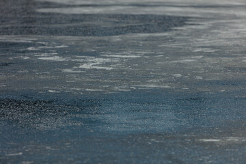 Close-up view of a frozen lake surface, showing ice patterns and scattered light.  A textured, slightly rough ice sheet.