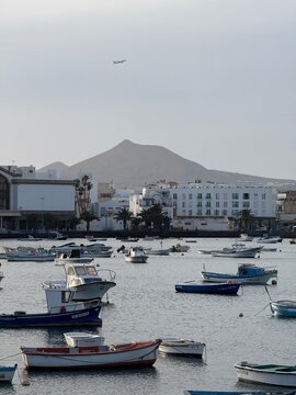 Escena costera en Arrecife, Lanzarote, con peque&ntilde;os barcos, edificios blancos y monta&ntilde;a al fondo