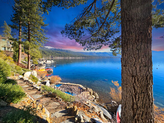 a gorgeous winter landscape at Lake Tahoe with blue lake water, lush green trees and plants and...
