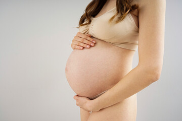 Beautiful pregnant woman in underwear on grey background.