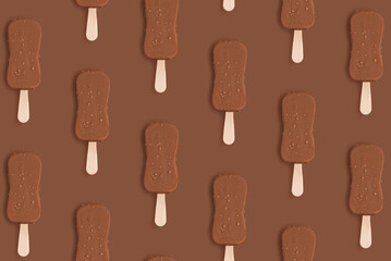 Pattern of chocolate ice cream on a stick with nuts and chocolate glaze on a brown background. Monochrome food photo concept