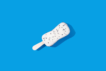 White chocolate ice cream on a stick on a blue background. Minimal food photo concept, top view